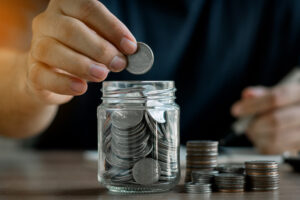 man putting money in savings pot stock image
